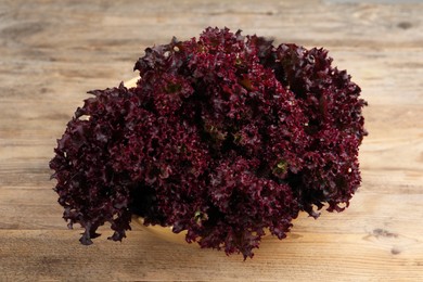 Bowl with fresh red coral lettuce on wooden table
