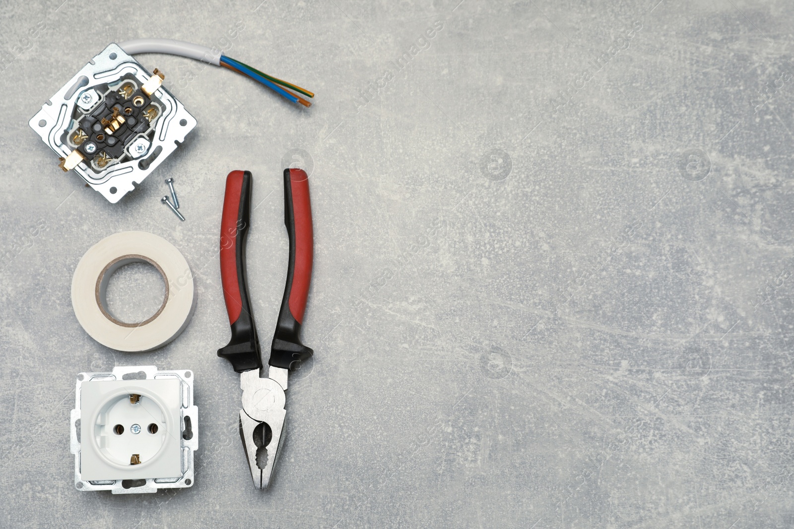 Photo of Power sockets, pliers and insulating tape on grey table, flat lay. Space for text