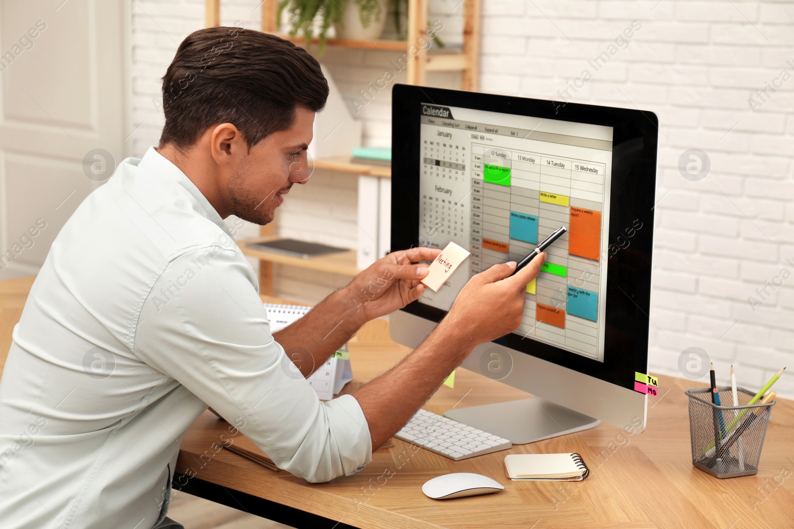 Photo of Handsome man using calendar app on computer in office