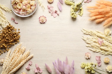 Frame of beautiful dried flowers on wooden background, flat lay. Space for text