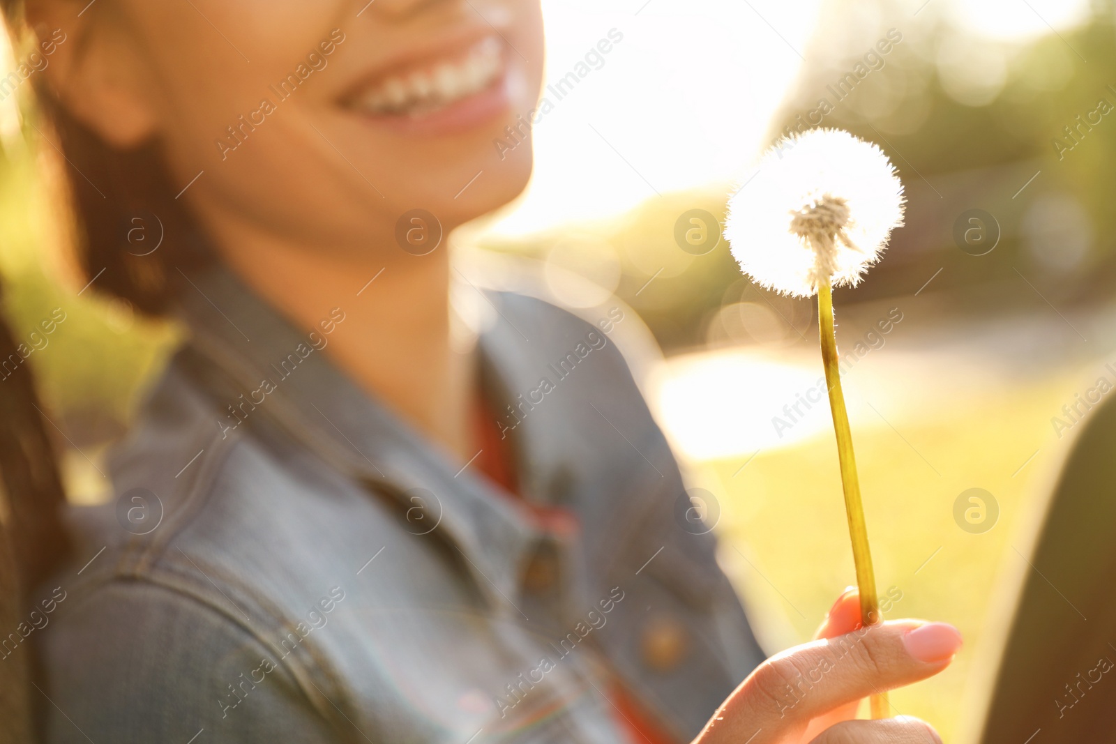 Photo of Young woman with dandelion in park on sunny day, closeup. Allergy free concept