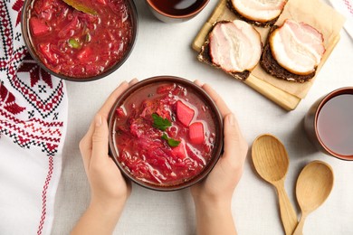 Photo of Woman with clay bowl of Ukrainian borsch at table, top view