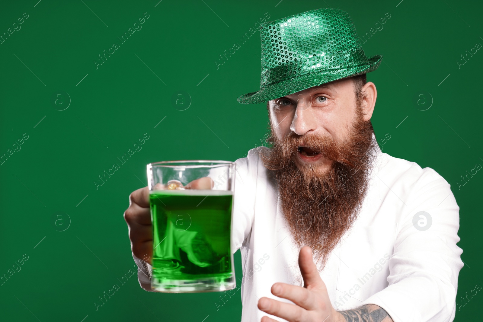 Photo of Bearded man with green beer on color background. St. Patrick's Day celebration