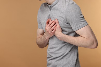 Photo of Man suffering from heart hurt on beige background, closeup. Space for text