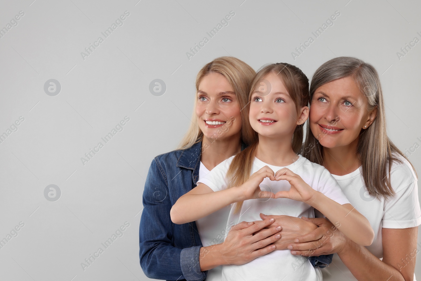 Photo of Three generations. Happy grandmother, her daughter and granddaughter on light gray background, space for text