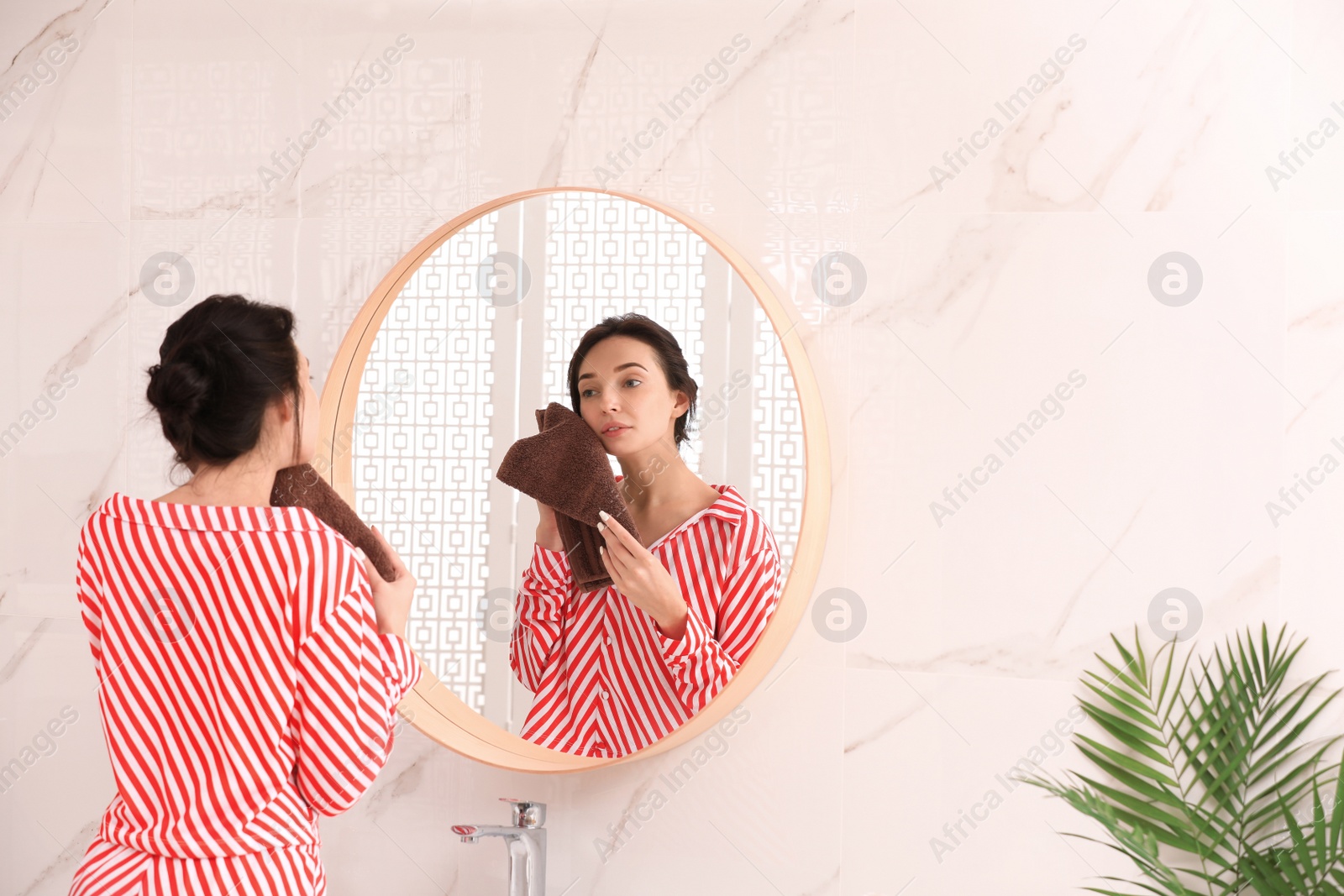 Photo of Young woman with towel near mirror in bathroom