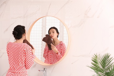 Photo of Young woman with towel near mirror in bathroom