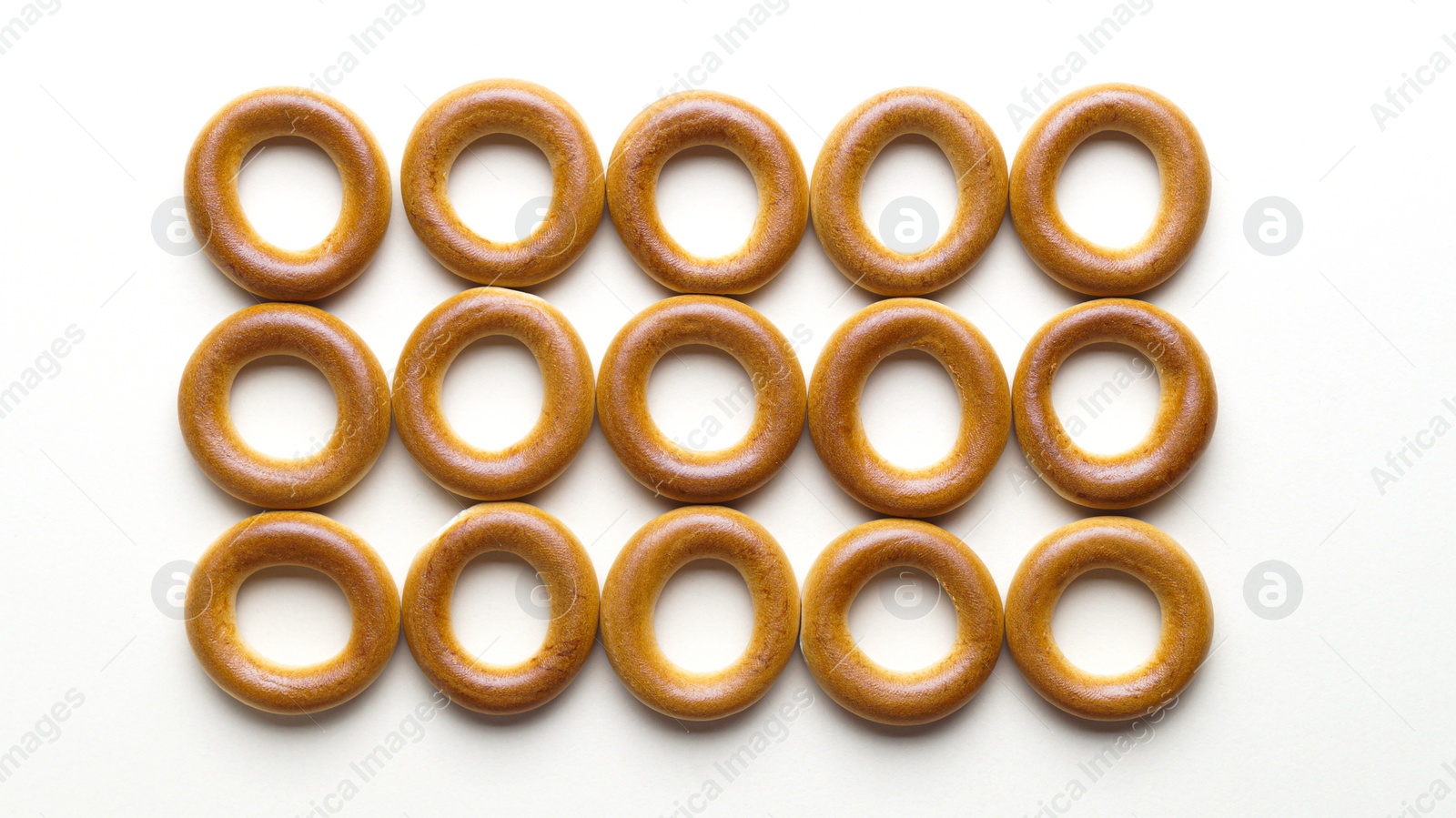 Photo of Tasty dry bagels (sushki) on light background, flat lay