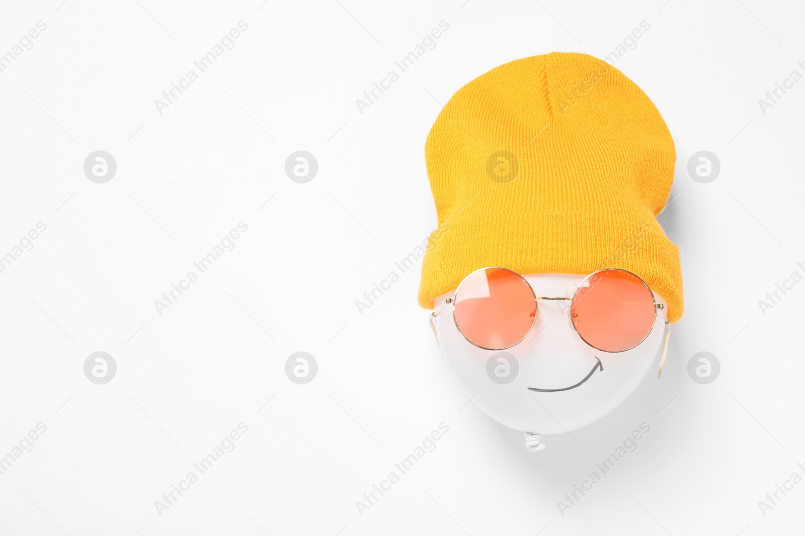 Photo of Funny face made of balloon, hat and sunglasses on white background, top view. Space for text