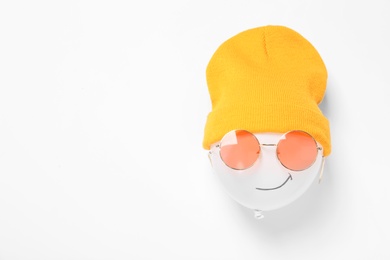 Funny face made of balloon, hat and sunglasses on white background, top view. Space for text