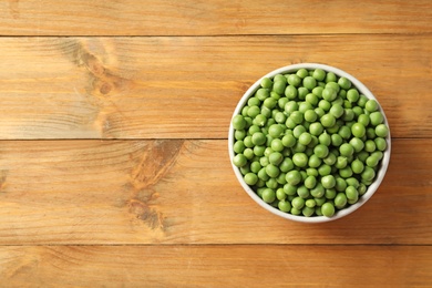 Photo of Bowl with green peas on wooden background, top view