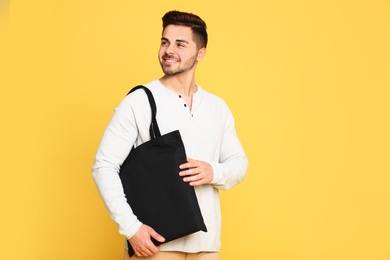 Portrait of young man with eco bag on yellow background. Space for text