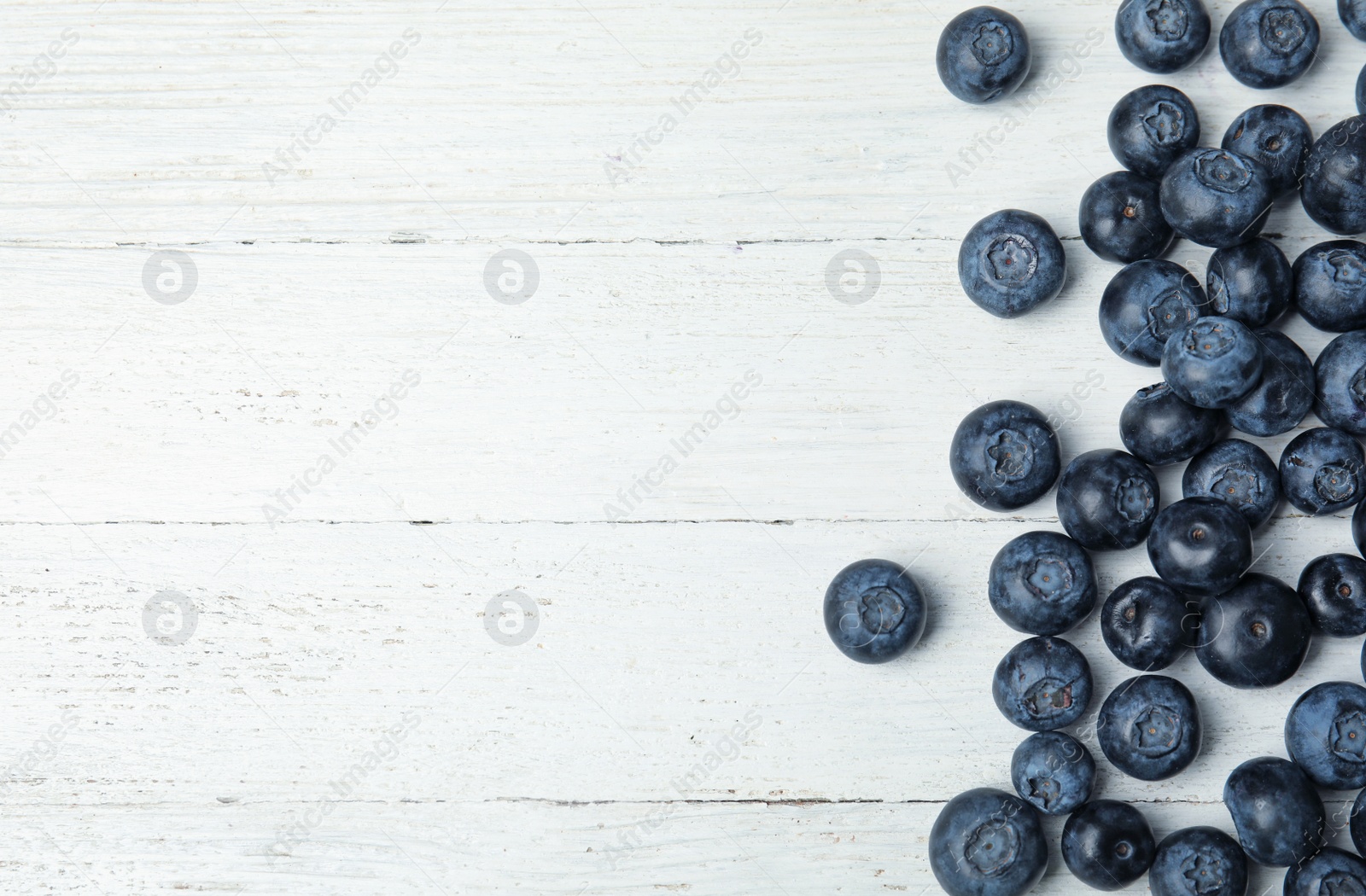 Photo of Tasty fresh blueberries on white wooden table, top view with space for text