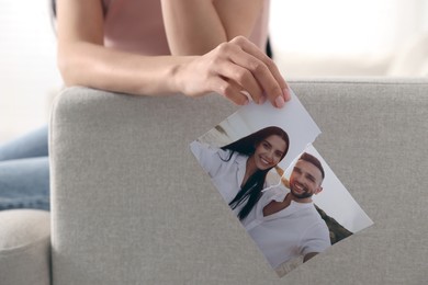 Photo of Woman holding torn photo on sofa, closeup. Divorce concept