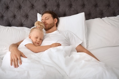 Photo of Father and his cute daughter sleeping in bed. Nap time