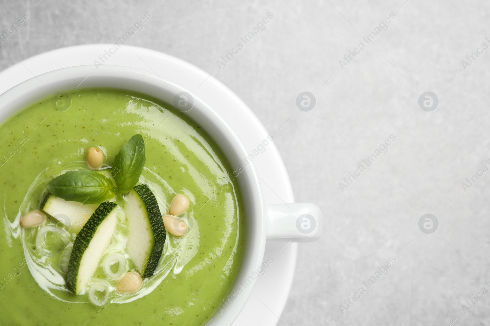 Photo of Tasty homemade zucchini cream soup on grey table, top view