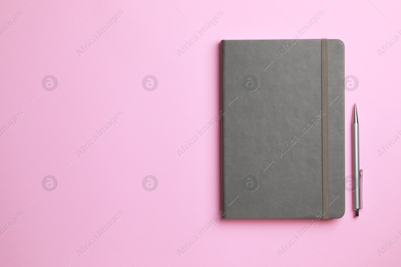 Photo of Notebook and pen on pale pink background, flat lay. Space for text