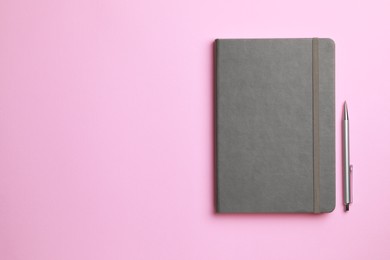 Photo of Notebook and pen on pale pink background, flat lay. Space for text