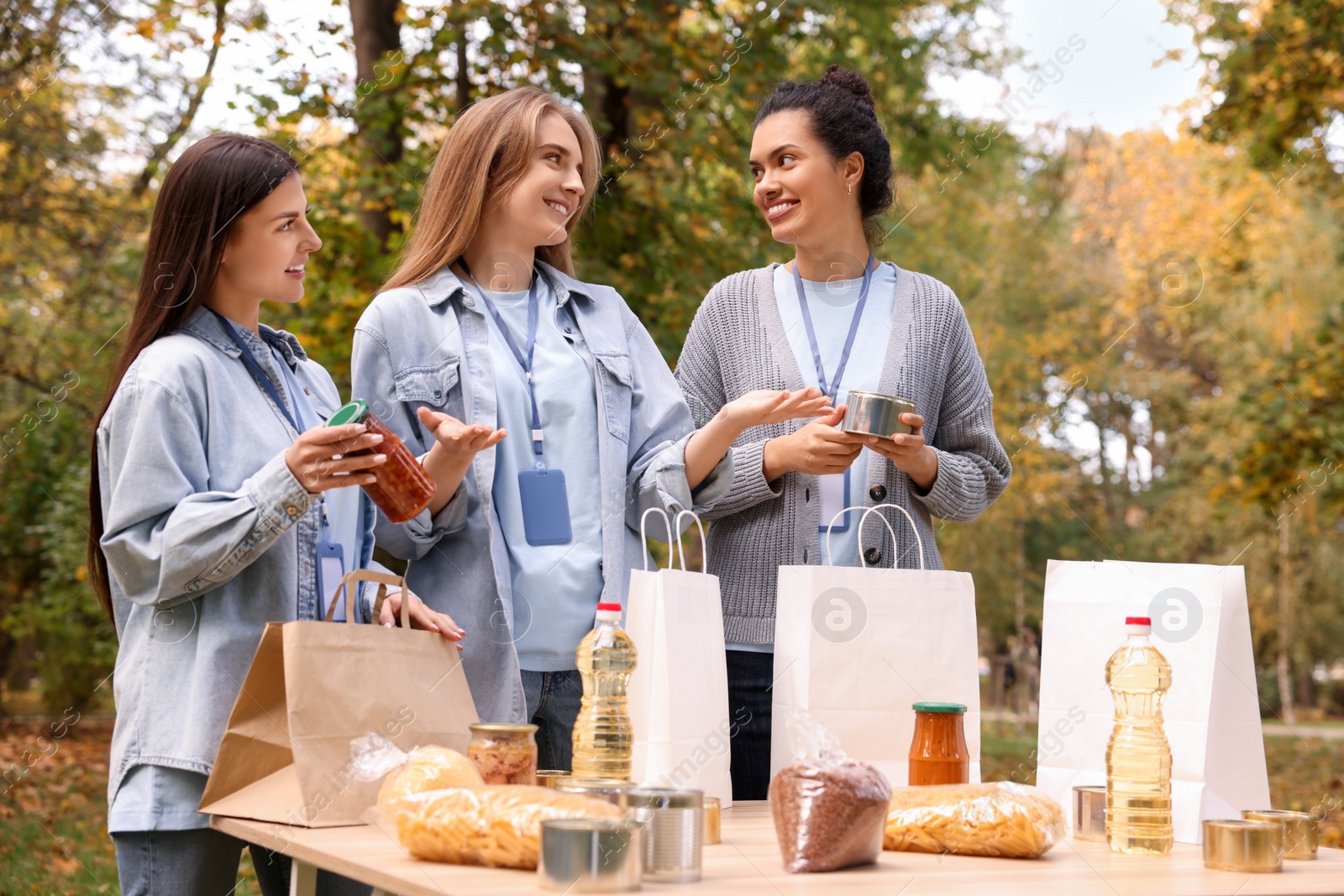 Photo of Group of volunteers packing food products at table in park