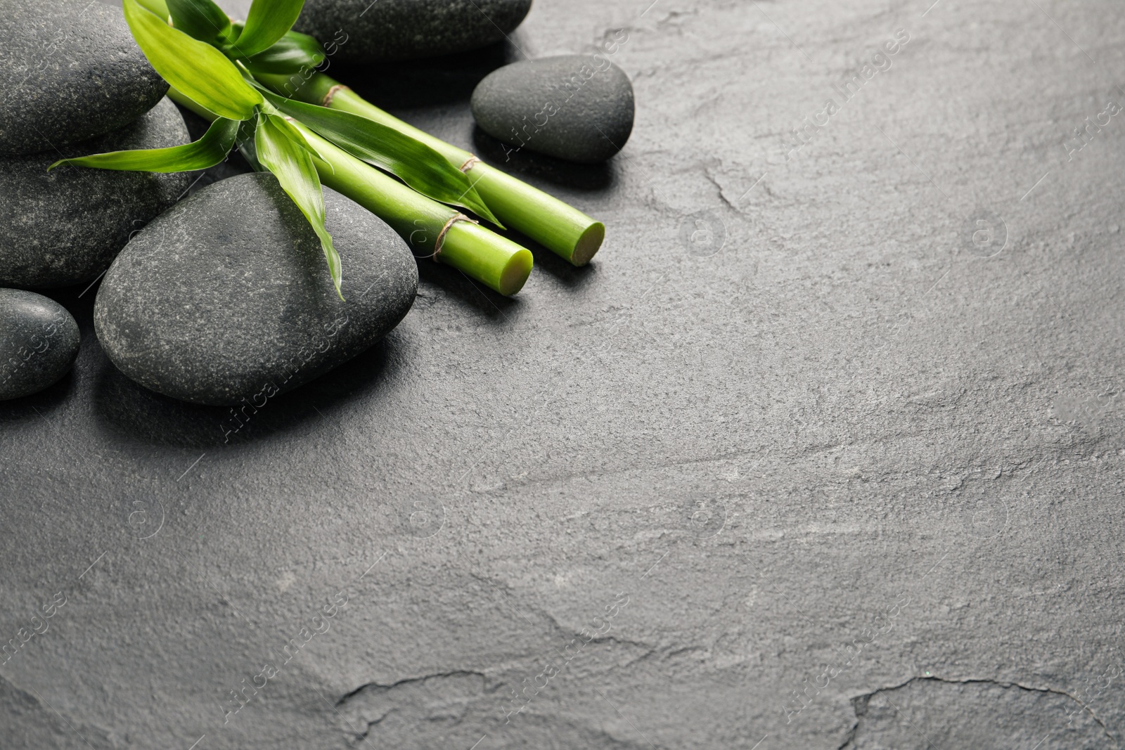 Photo of Spa stones and bamboo stems on grey table. Space for text