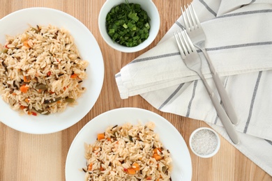 Delicious rice with vegetables served on wooden table, flat lay. Multi cooker recipes