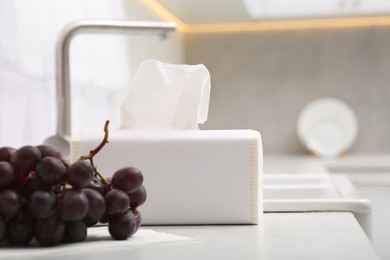 Photo of Package of paper towels and ripe grapes near sink in kitchen