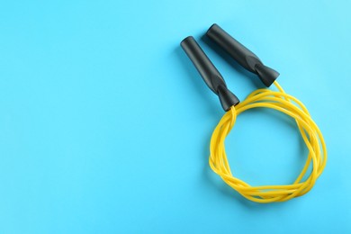 Photo of Skipping rope on light blue background, top view. Space for text