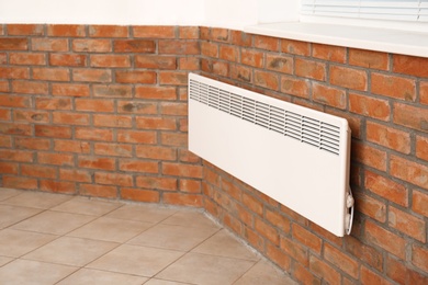 Photo of Modern heating convector on brick wall indoors