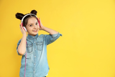Cute girl enjoying music in headphones on color background. Space for text