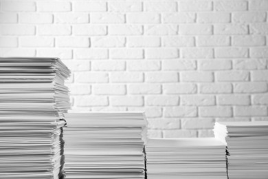 Photo of Stacks of paper sheets near white brick wall, space for text