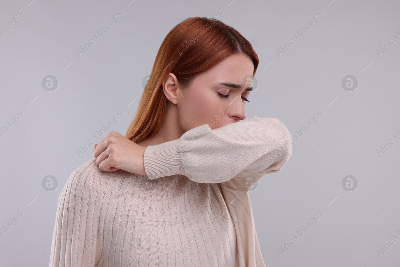 Photo of Woman coughing on light grey background. Cold symptoms