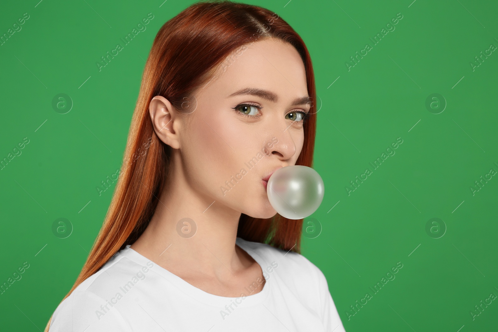 Photo of Beautiful woman blowing bubble gum on green background, space for text