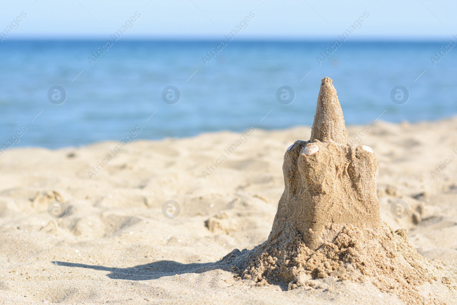 Photo of Beach with sand castle near sea on sunny day. Space for text