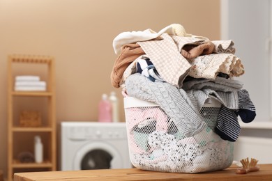 Laundry basket with baby clothes on wooden table in bathroom, space for text