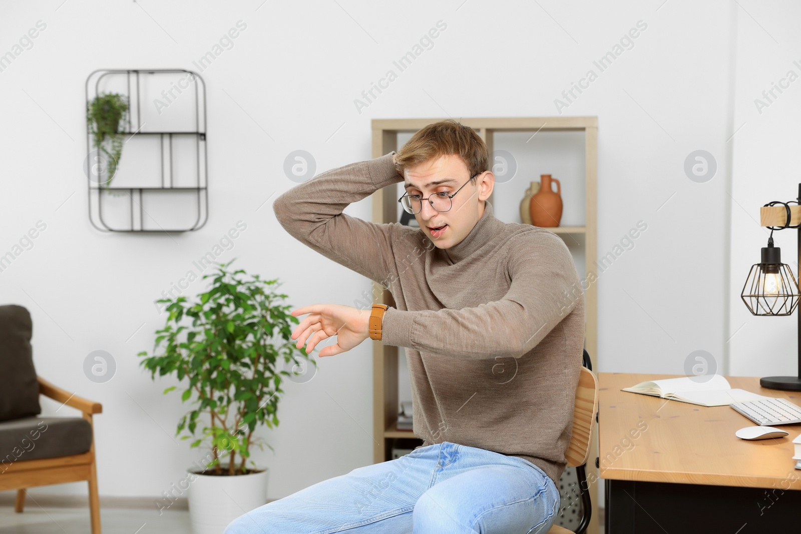 Photo of Emotional young man checking time in office. Being late