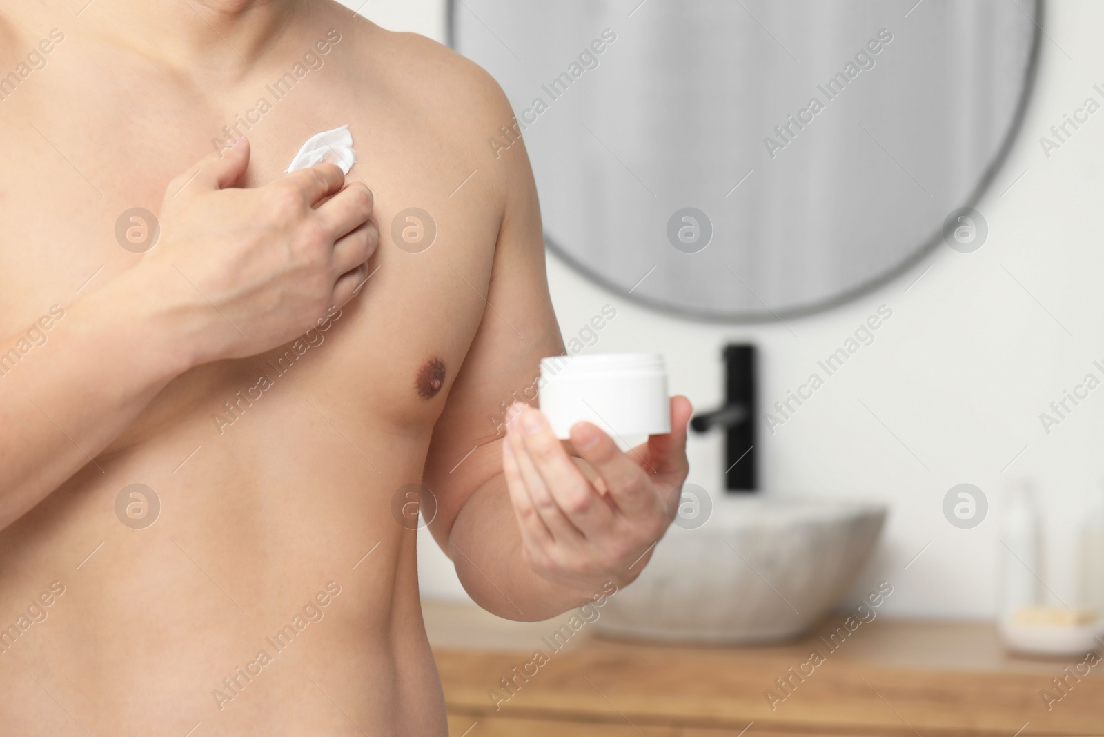 Photo of Man applying body cream onto his chest indoors, closeup. Space for text