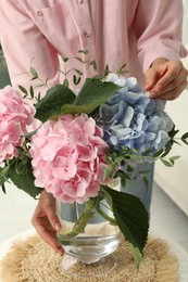 Photo of Woman with bouquet of beautiful hortensia flowers in living room, closeup