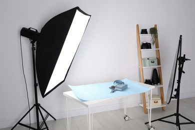 Professional lighting equipment near table with fashionable women's accessories in photo studio