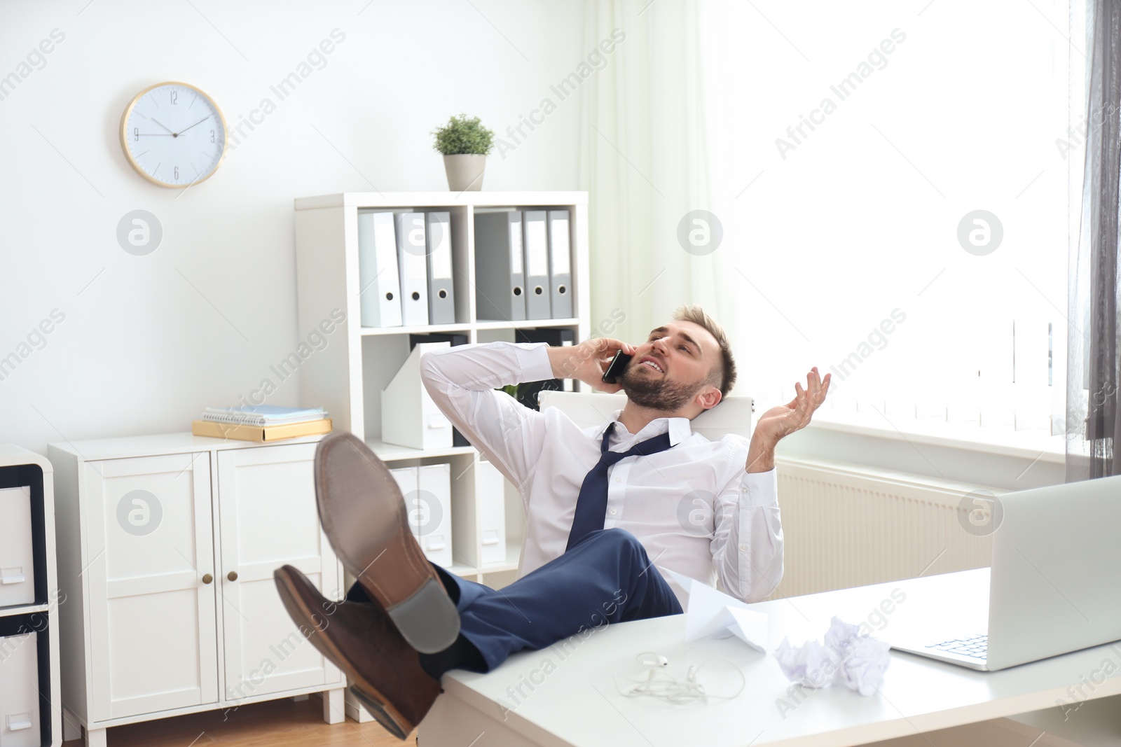 Photo of Lazy young man talking on smartphone in office