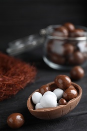 Photo of Half of tasty chocolate egg with candies on black wooden table, space for text