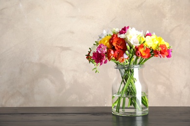 Photo of Bouquet of spring freesia flowers in vase on table. Space for text