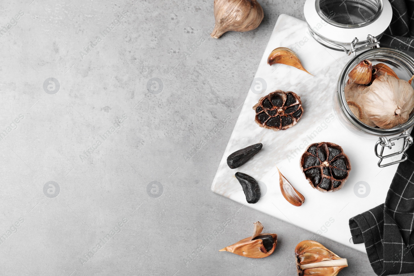 Photo of Flat lay composition with black garlic and space for text on grey table