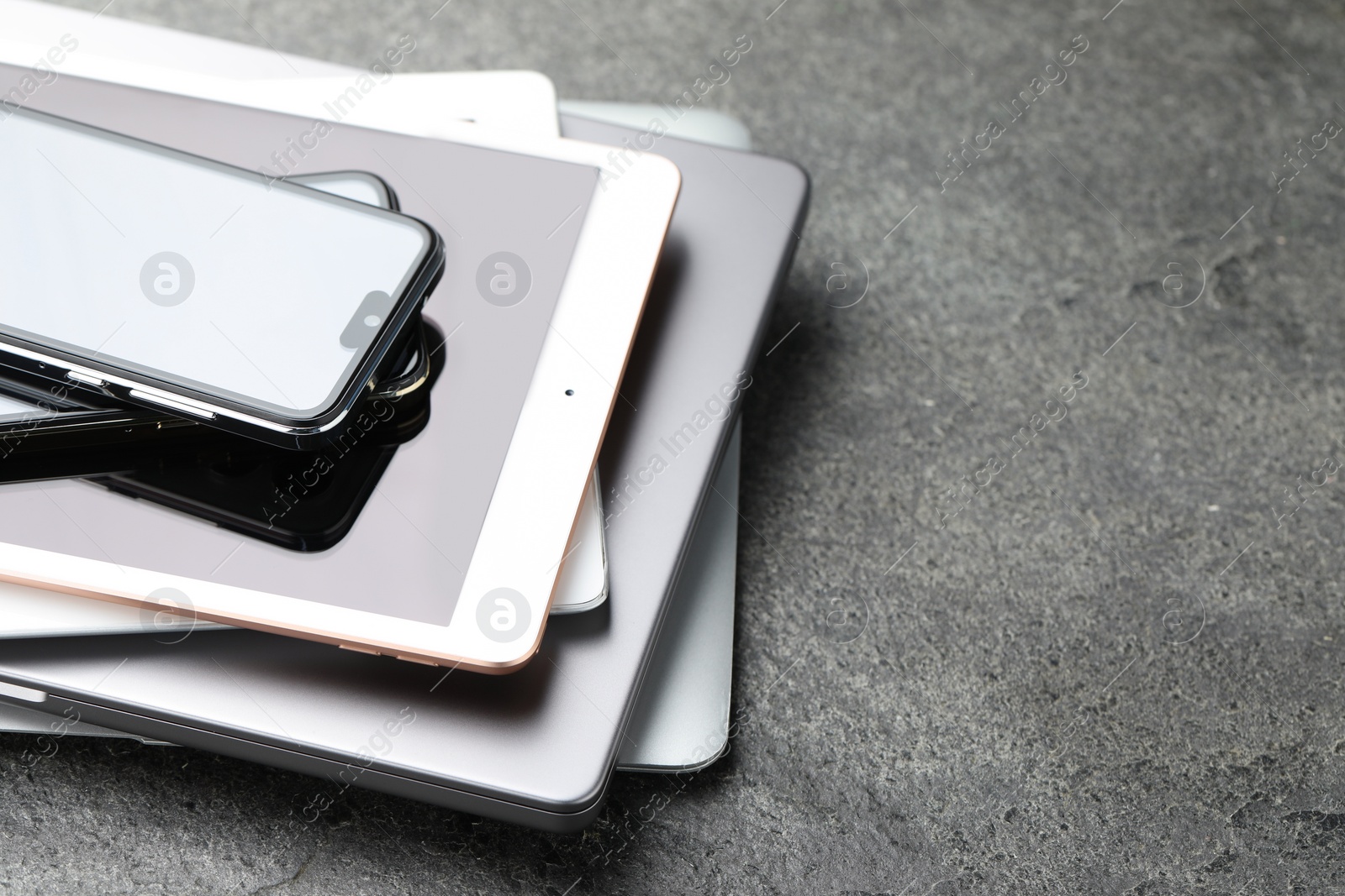 Photo of Stack of electronic devices on grey table, closeup. Space for text