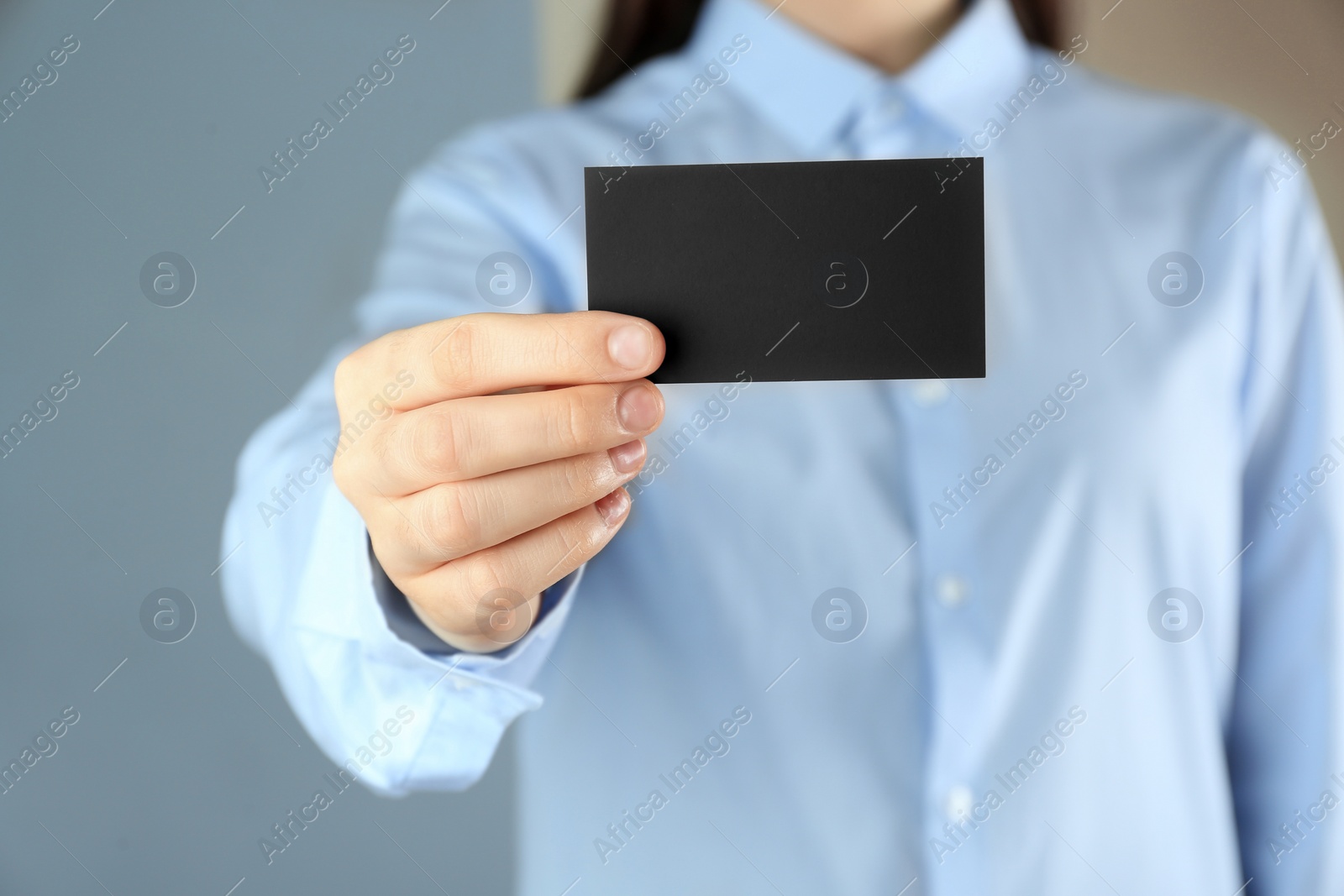 Photo of Woman holding blank business card on grey background, closeup. Mockup for design