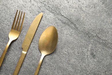 Stylish golden cutlery on grey table, flat lay. Space for text