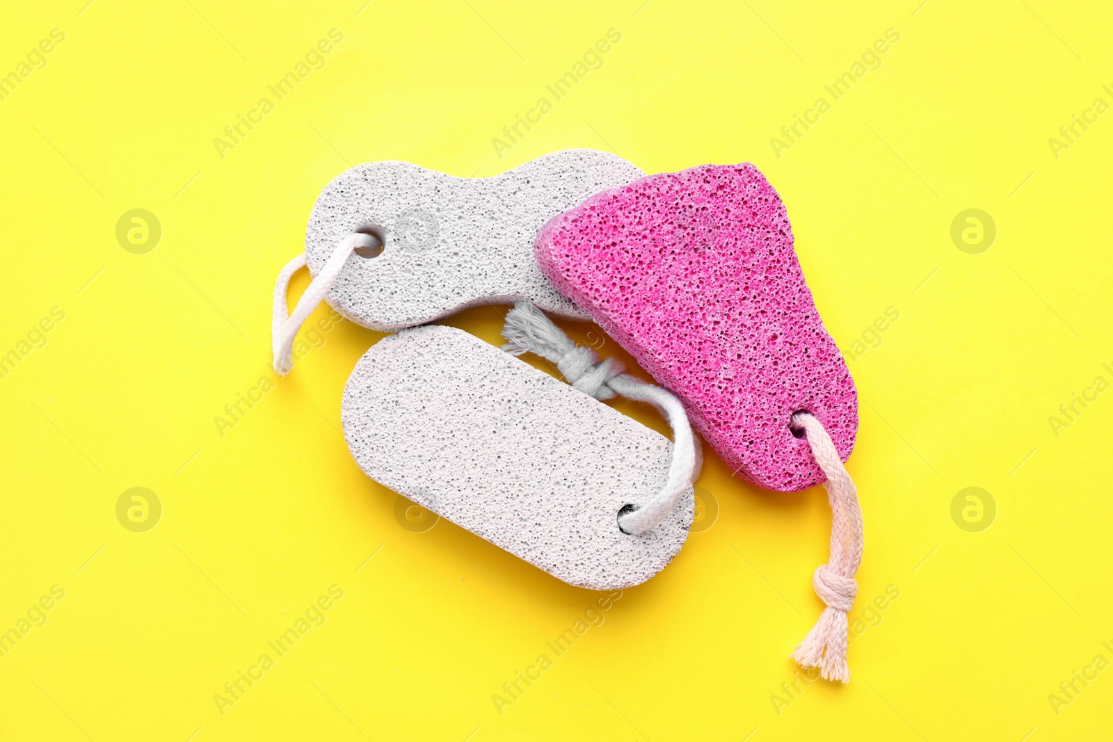 Photo of Different pumice stones on yellow background, flat lay