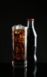 Bottle and glass of refreshing soda water on black background