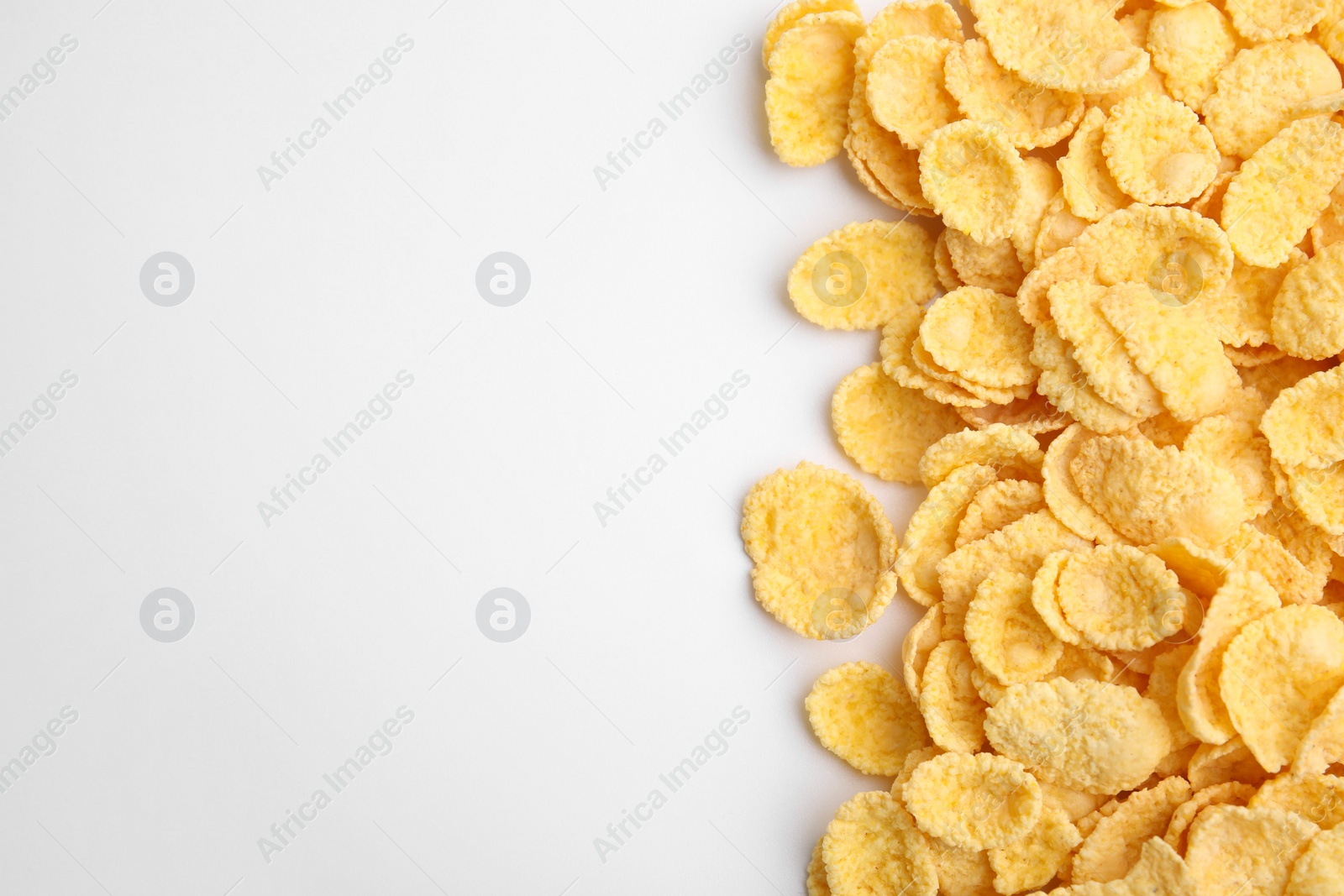 Photo of Breakfast cereal. Tasty corn flakes on white background, flat lay. Space for text