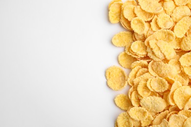 Photo of Breakfast cereal. Tasty corn flakes on white background, flat lay. Space for text