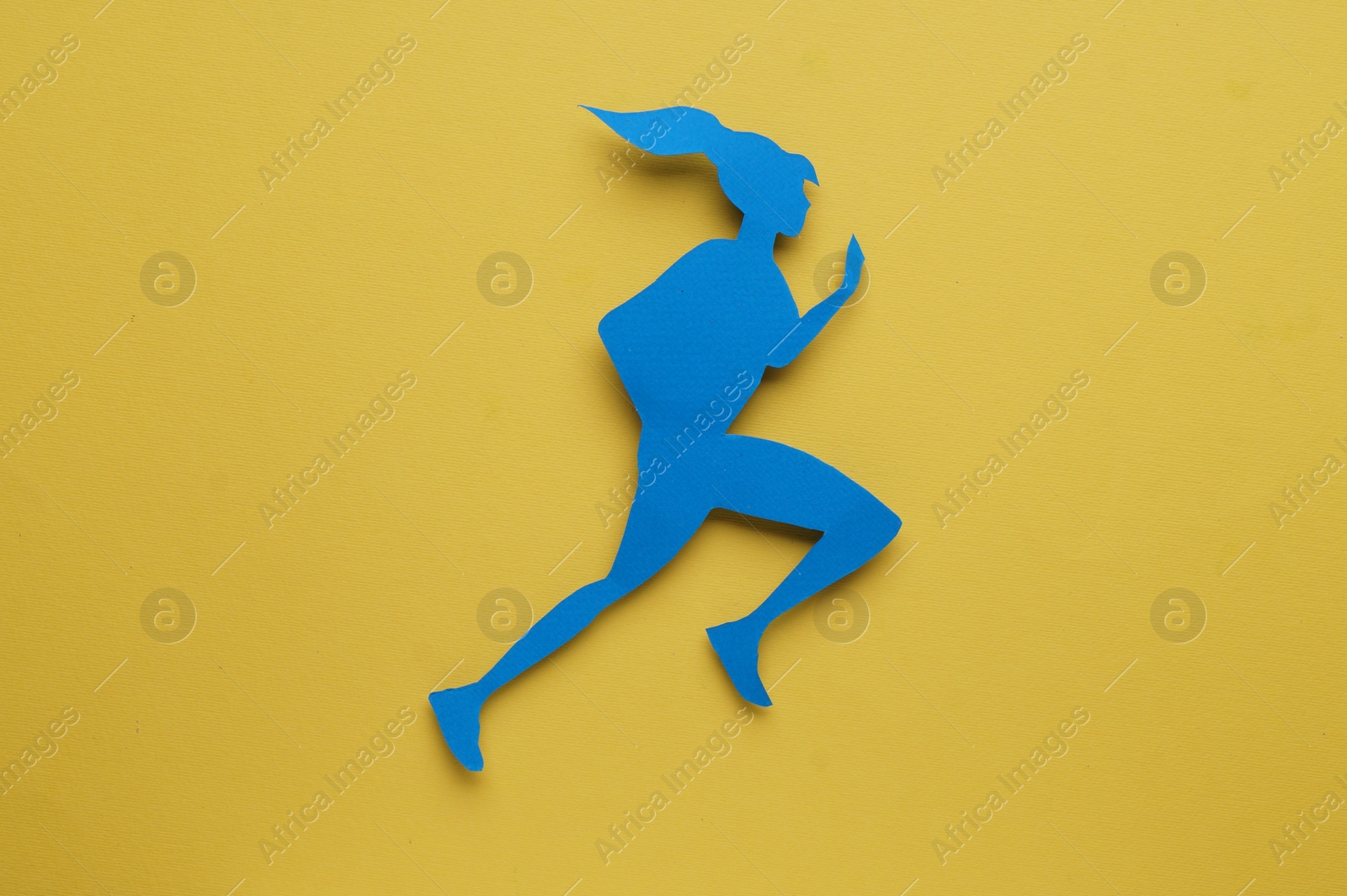 Photo of Sportswoman paper figure on yellow background, top view. Woman`s health